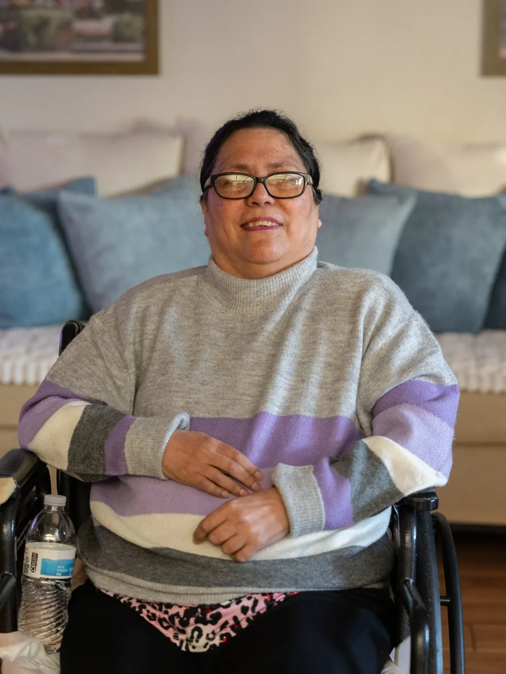 Smiling resident in wheelchair relaxing in comfortable living room setting.