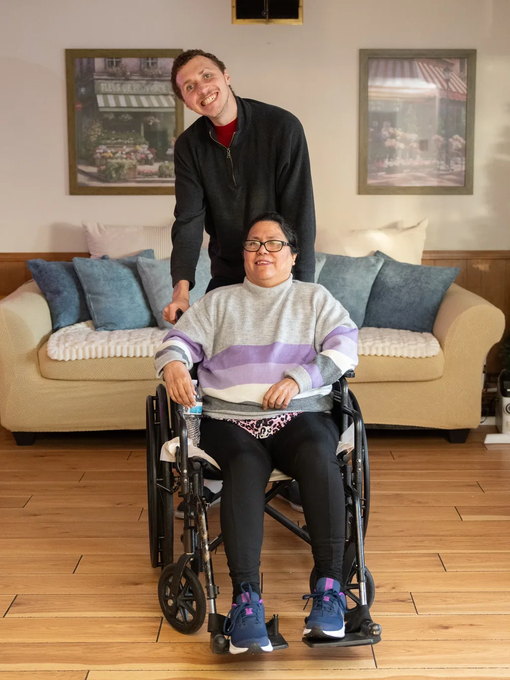 Caregiver and resident smiling together in a cozy residential care home living room.